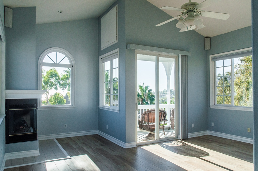 Blue walls and white windows with a sliding door leading to a second floor balcony at a Naples Beach home in Florida.
