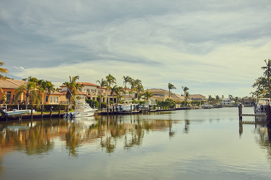 Waterfront homes in Naples facing the bay with boats attached to docks of each house