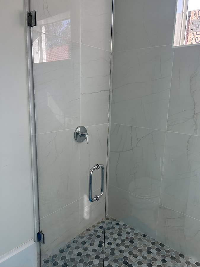 bathroom with clear glass doors and hexagon floor tiles with marble long square tiles