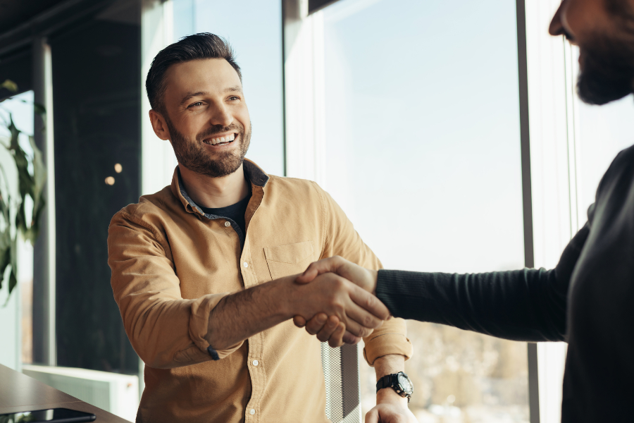 Investor smiling as he shakes realtor's hand after discussing how to maximize your ROI